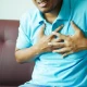 Man clutching chest in pain, indicating chest pain.