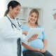 Doctor discussing with pregnant patient using tablet.