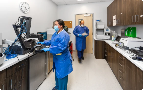 Scientists in lab coats using equipment in a medical laboratory.